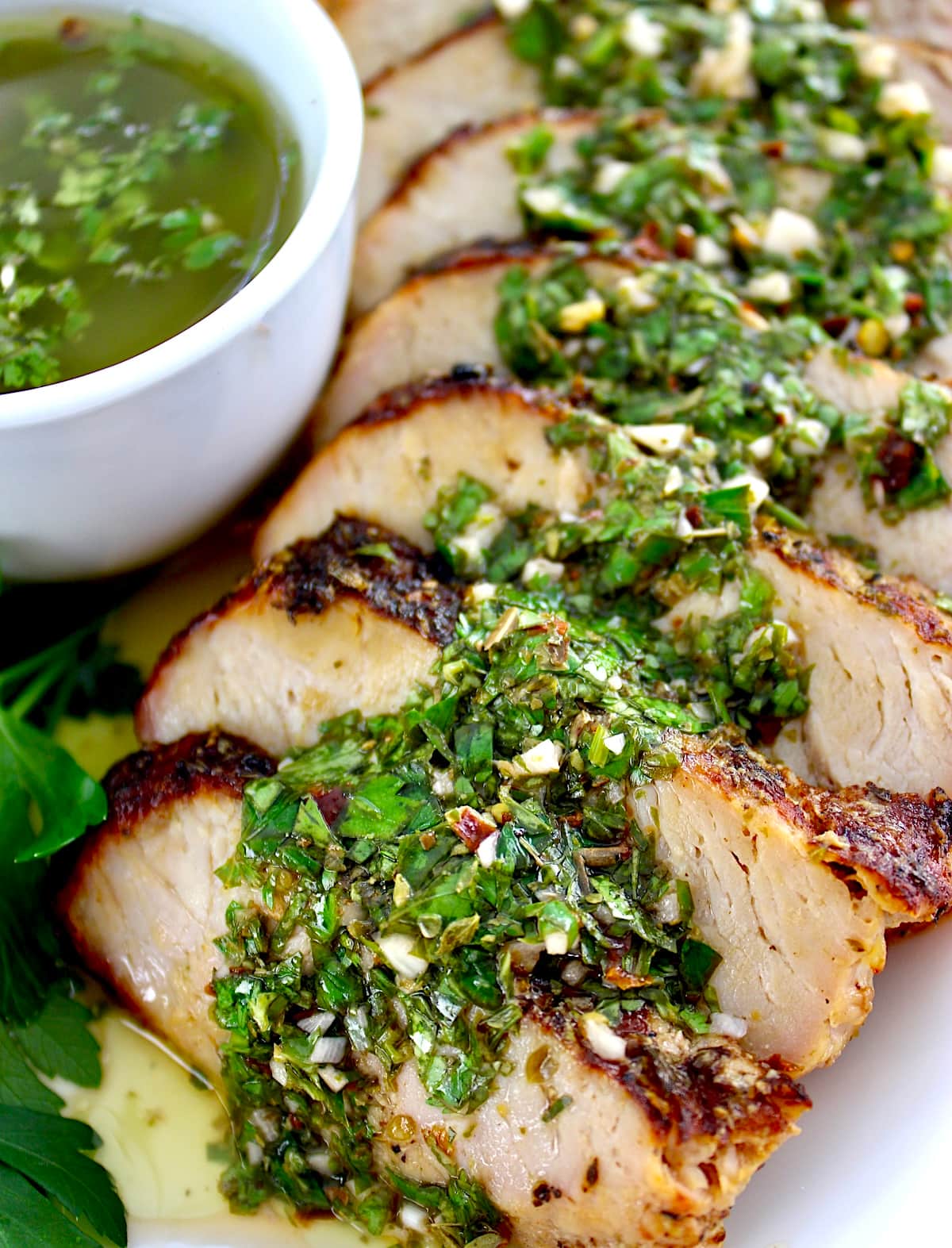 Grilled Pork Tenderloin with Chimichurri sliced on white plate with sauce in white cup