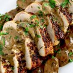 sliced Herb Crusted Pork Tenderloin with Mushroom Gravy with chopped parsley on top