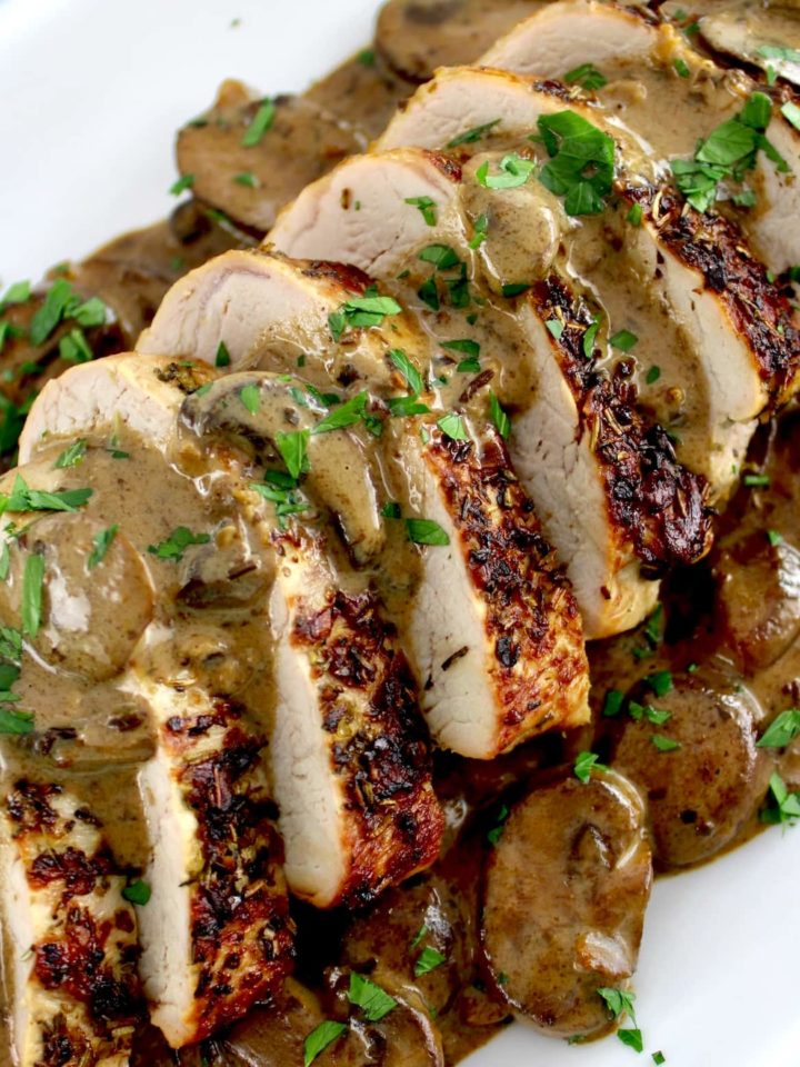 sliced Herb Crusted Pork Tenderloin with Mushroom Gravy with chopped parsley on top
