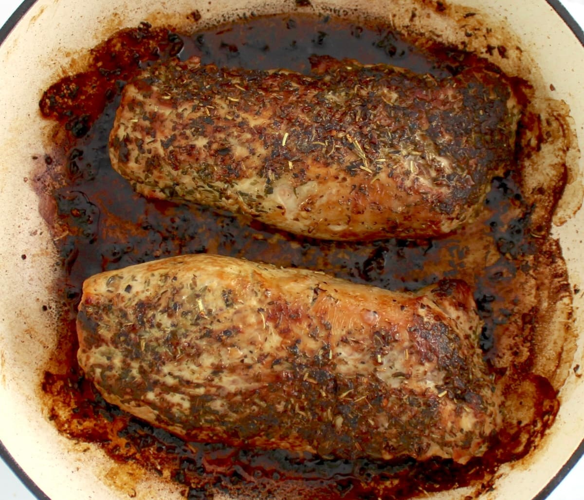 2 cooked herb crusted pork tenderloins in pan