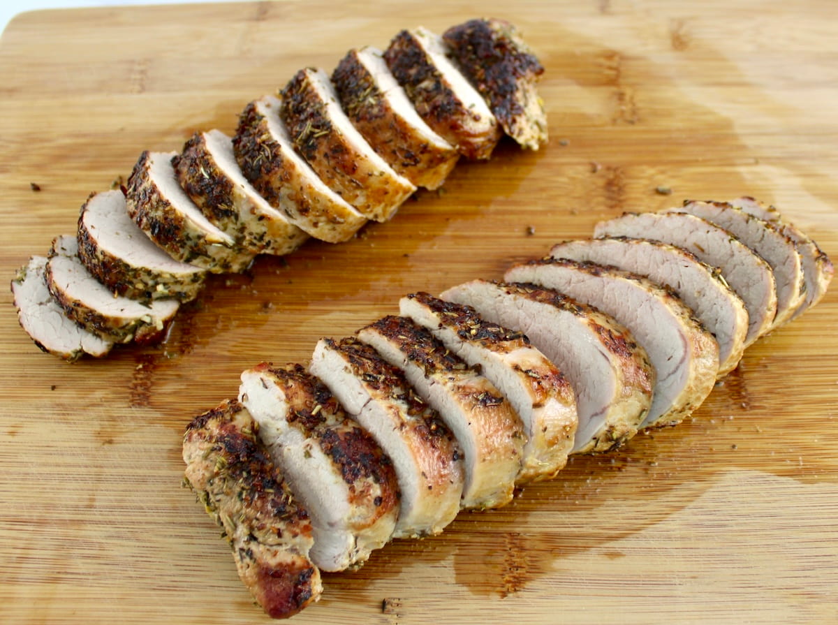 2 herb crusted pork tenderloins sliced on cutting board