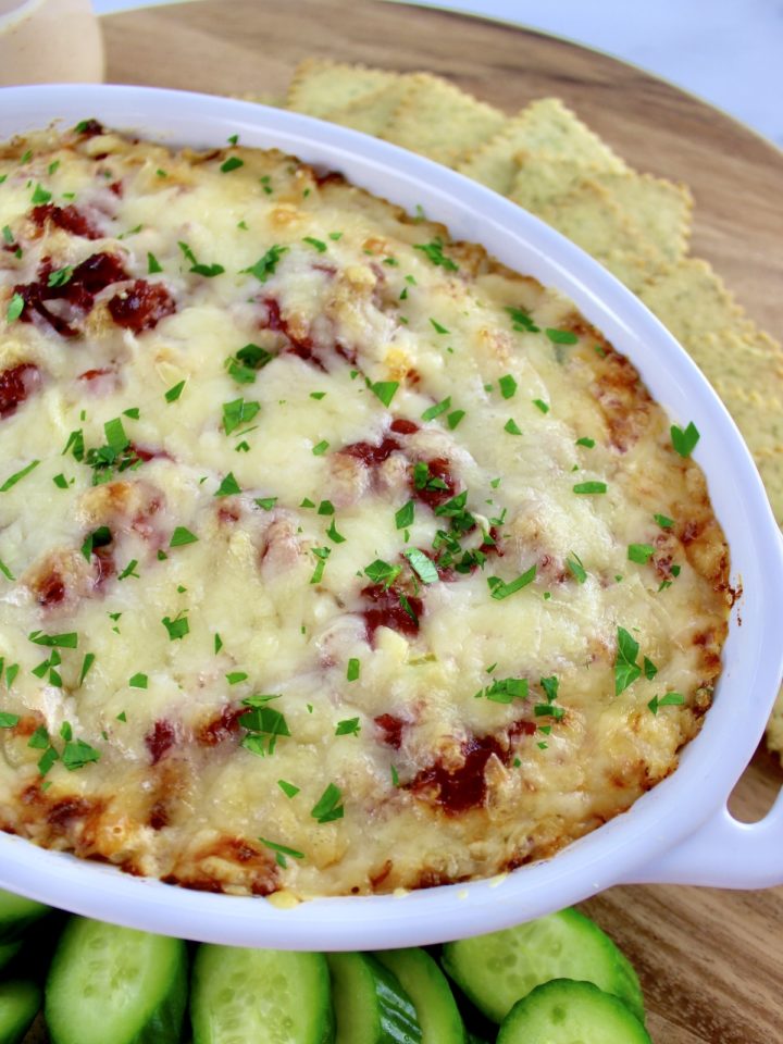 overhead view of Hot Reuben Dip in white casserole with crackers, cucumber and celery around