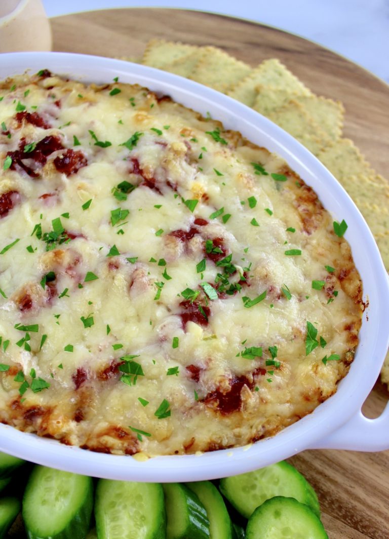 overhead view of Hot Reuben Dip in white casserole with crackers, cucumber and celery around