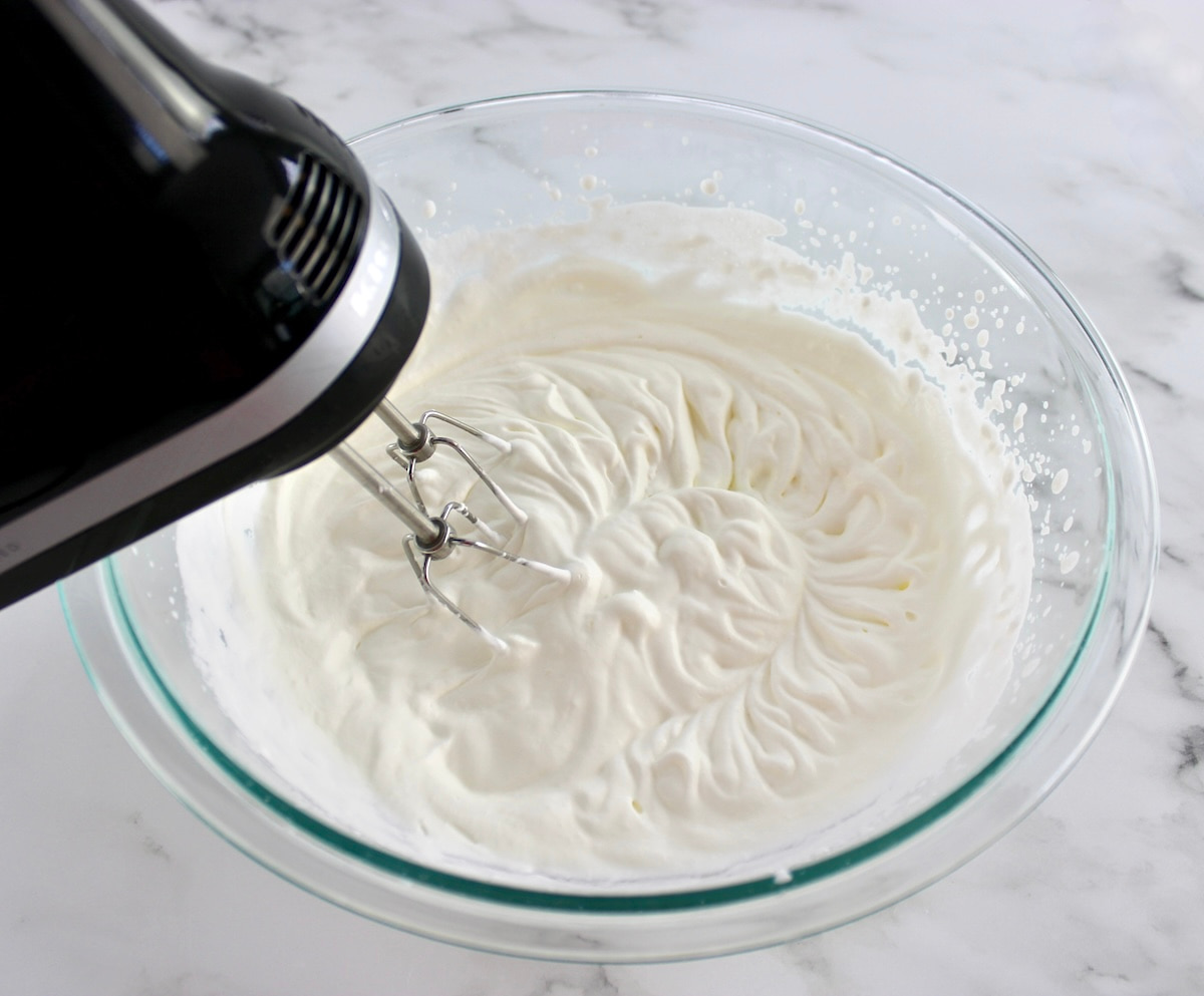 whip cream being mixed in glass bowl with hand mixer