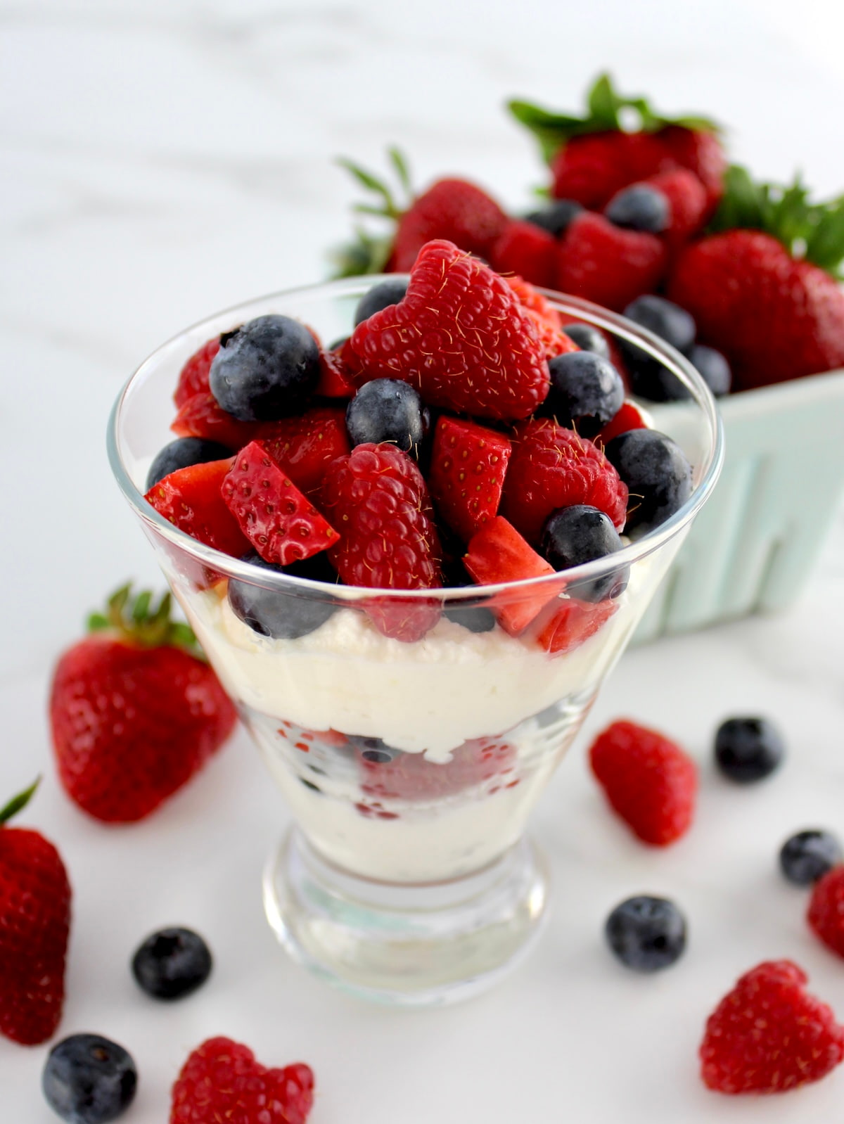side view of Keto Berries and Cream in layers in glass with berries in back