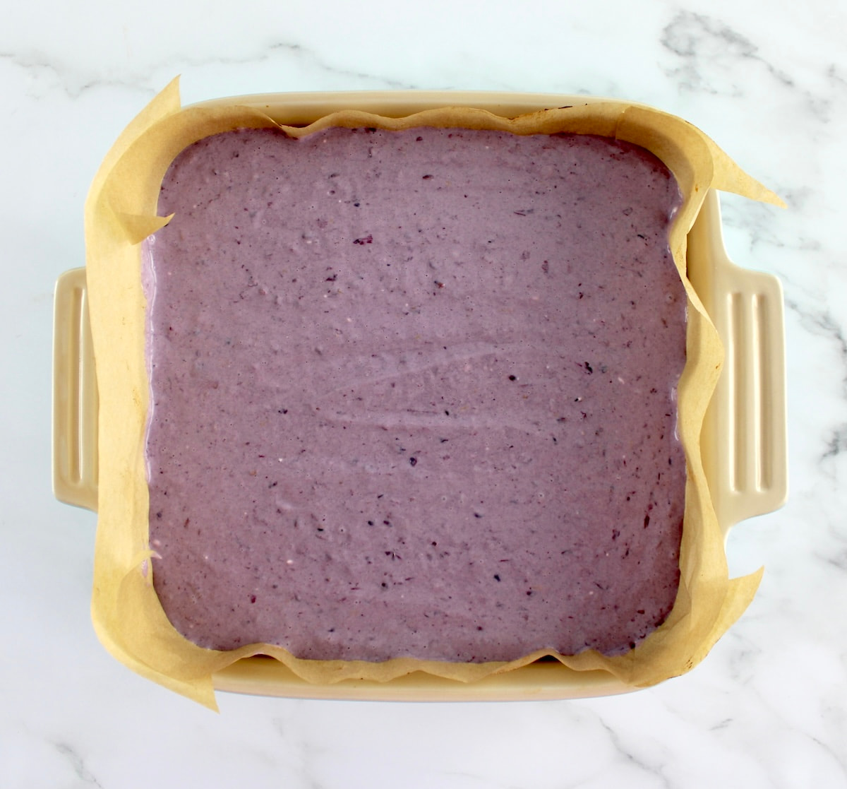 Blackberry Cheesecake Bars in baking dish lined with parchment paper unbaked