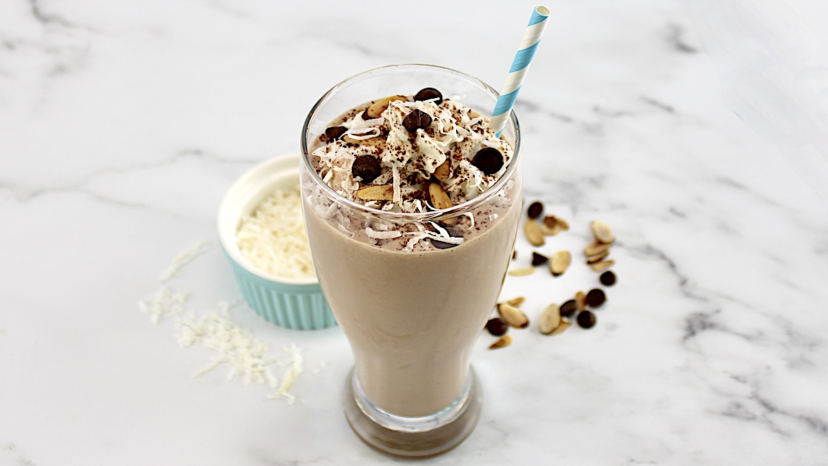 Almond Joy Protein Shake in glass with blue straw