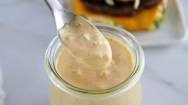 Big Mac Sauce being spooned out of open glass jar with burger in back