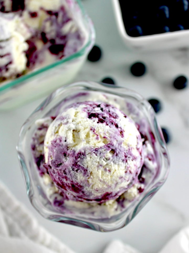 overhead view of Blueberry Vanilla Swirl Ice Cream in glass with blueberries in back