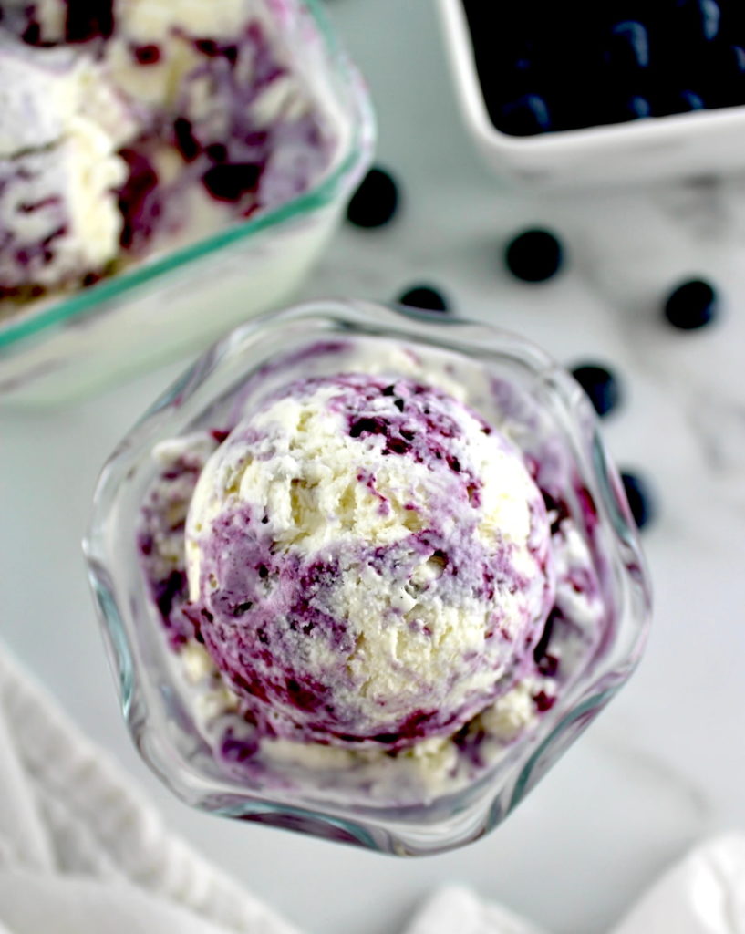 overhead view of Blueberry Vanilla Swirl Ice Cream in glass with blueberries in back