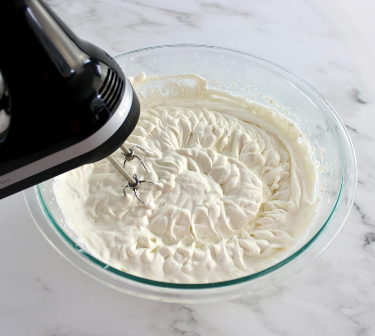 vanilla ice cream base in glass bowl with hand mixer