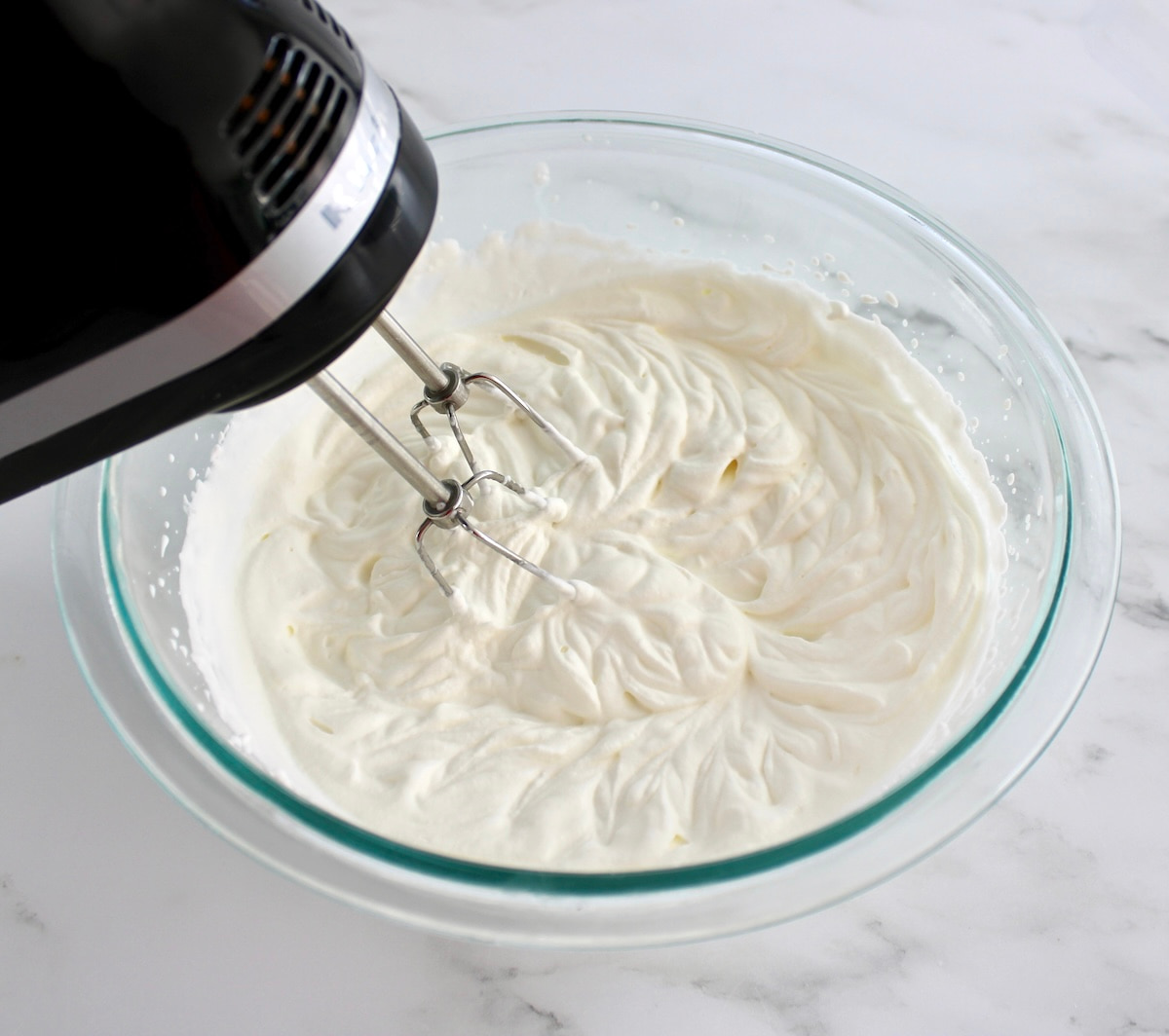 cream being whipped in glass bowl with hand mixer