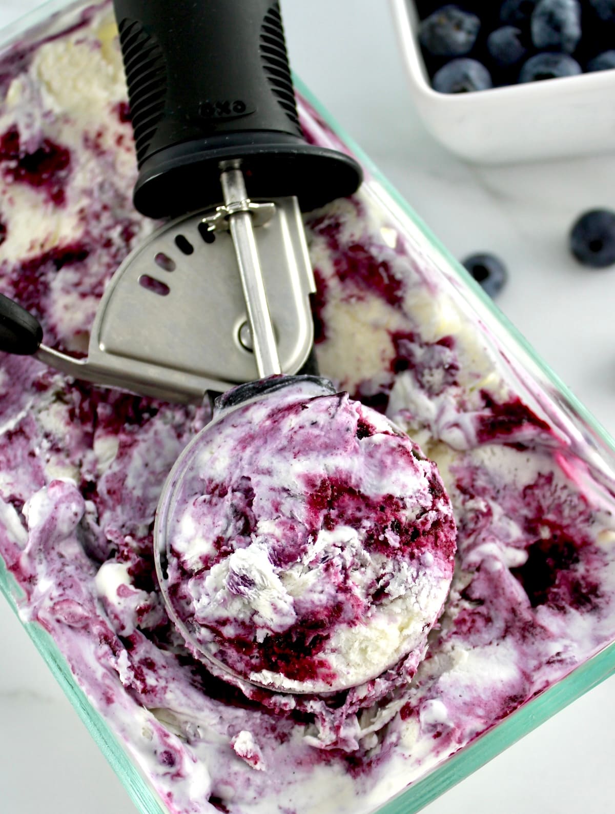 overhead view of Blueberry Vanilla Swirl Ice Cream in glass loaf pan with ice cream scoop