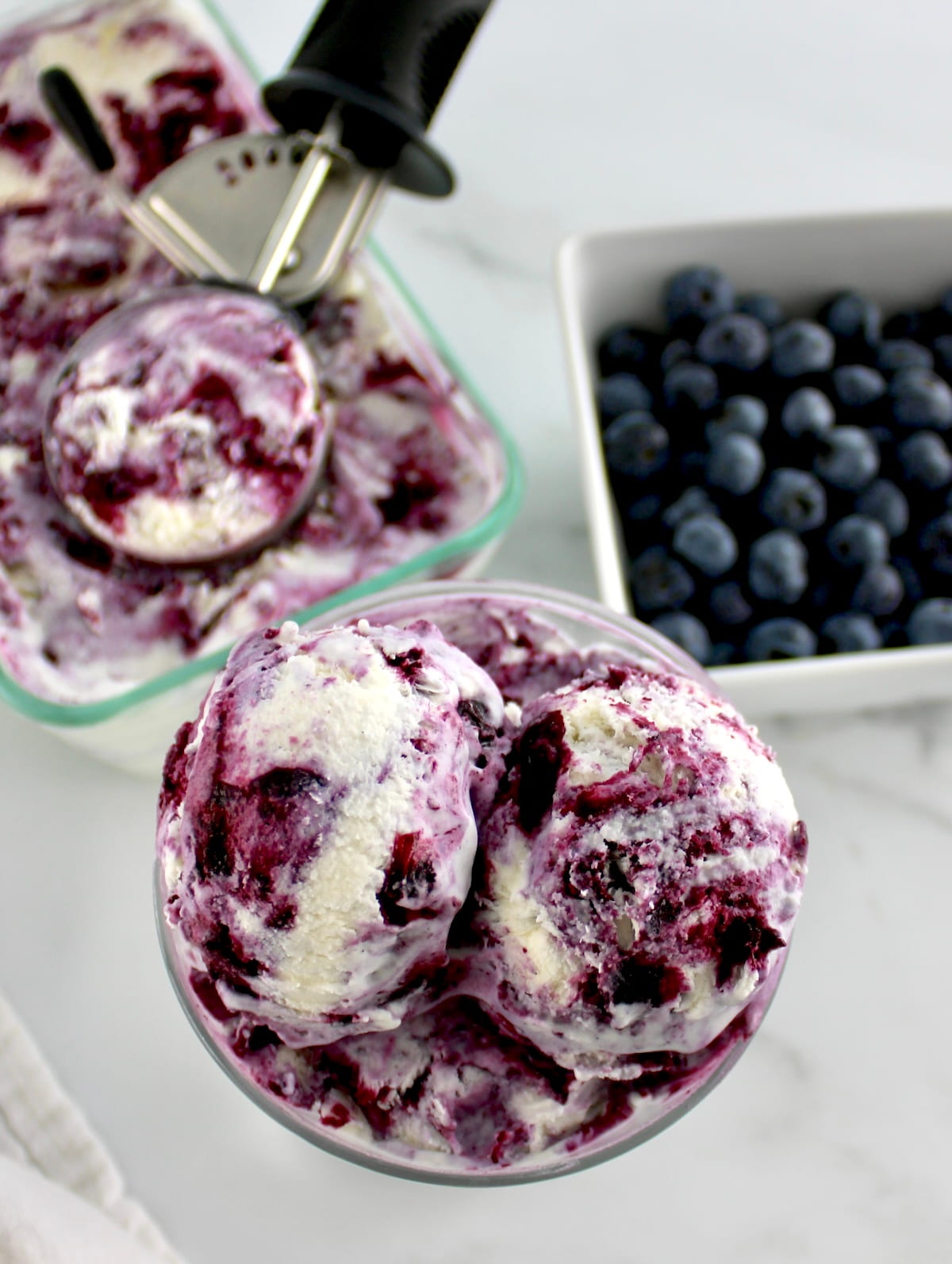 overhead view of Blueberry Vanilla Swirl Ice Cream in glass with blueberries and more ice cream in back