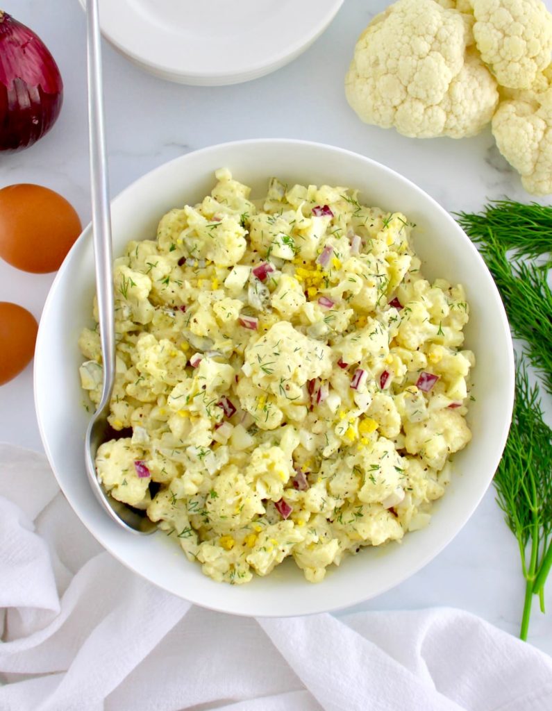 Cauliflower Potato Salad in white bowl with serving spoon