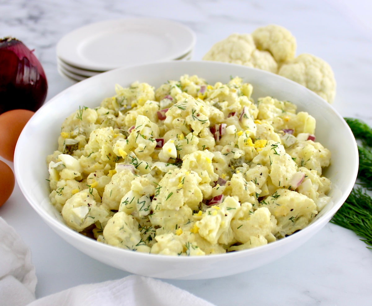 Cauliflower Potato Salad in white bowl with chopped fresh dill on top