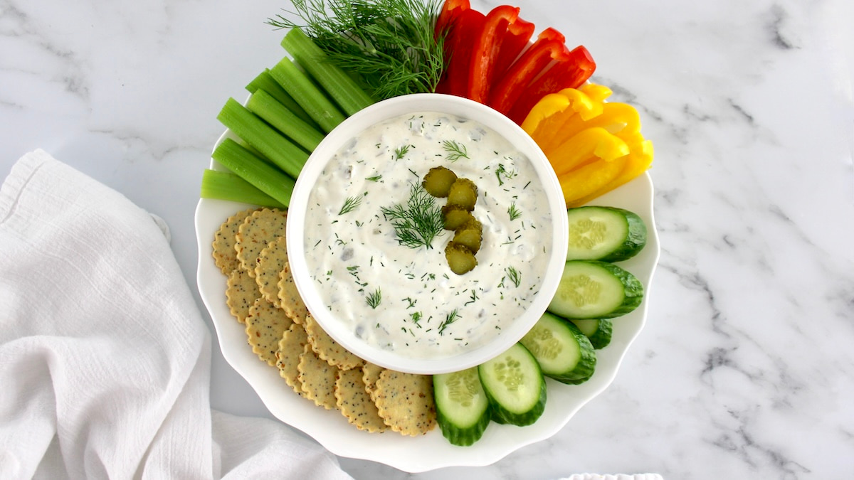 Dill Pickle Dip in white bowl with fresh veggies around