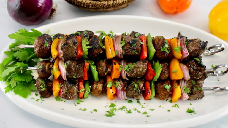 grilled beef kebabs on white plate with parsley garnish