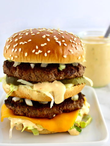 Keto Big Mac on white plate with sauce in back
