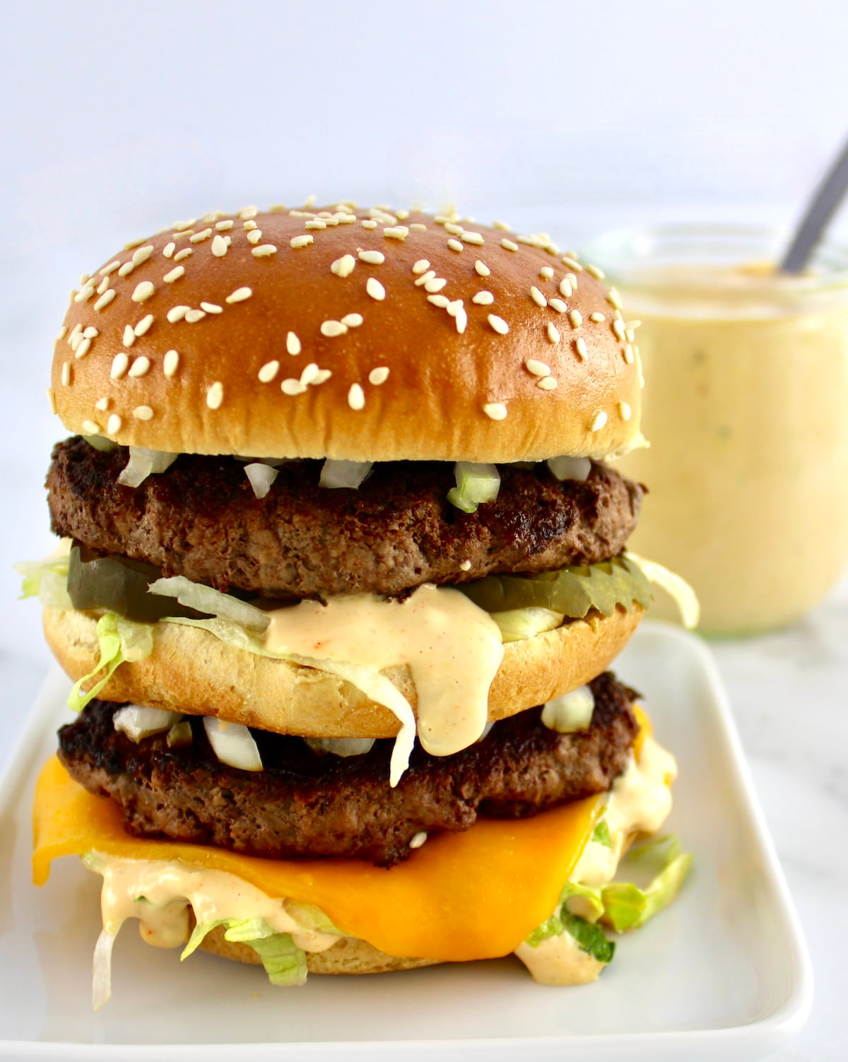 Keto Big Mac on white plate with sauce in back