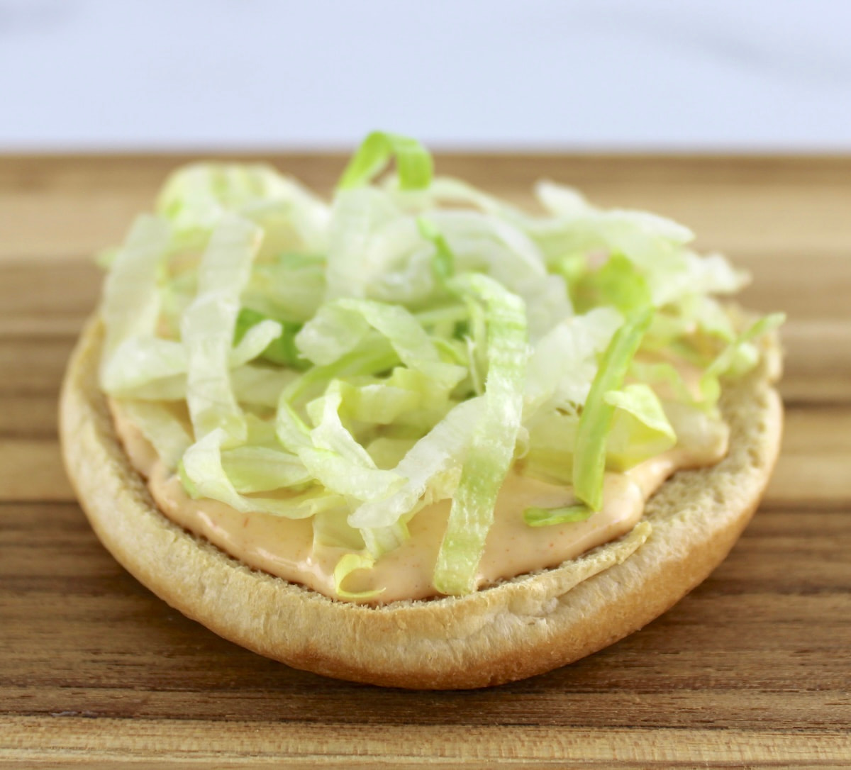 bottom hamburger bun with big mac sauce and lettuce on top