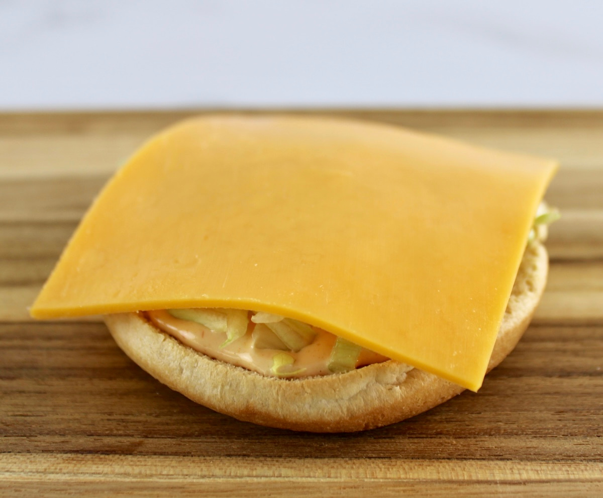 bottom hamburger bun with sauce, lettuce and cheese