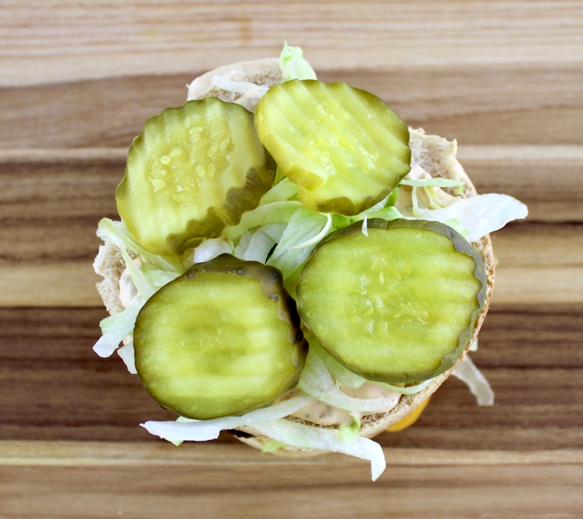 4 pickles on top of lettuce and burger bun