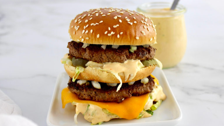 side view of Keto Big Mac on white plate with sauce in back