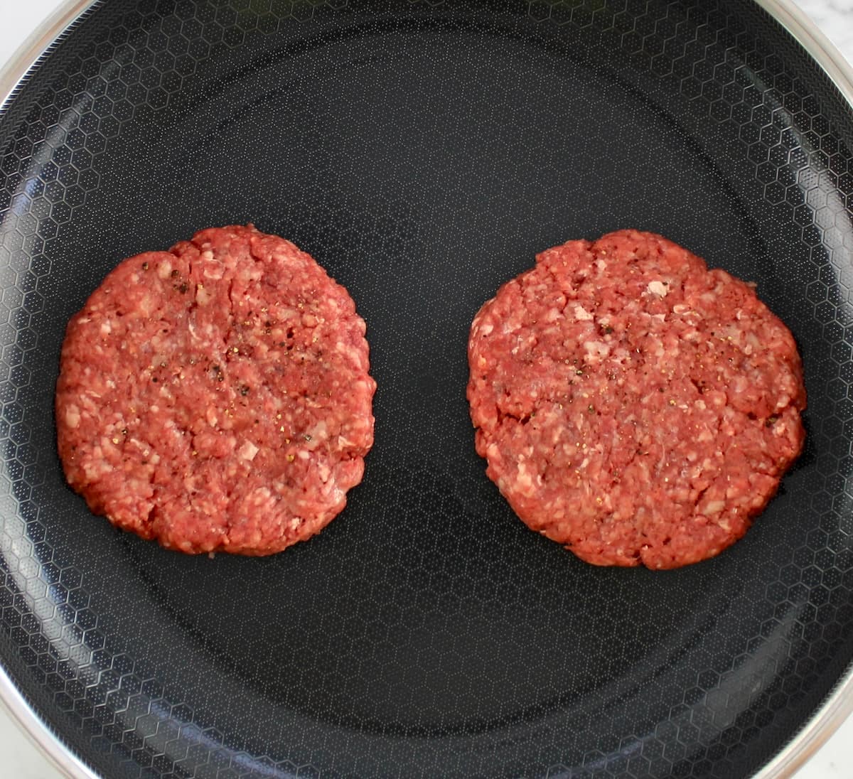 2 raw hamburger patties in skillet
