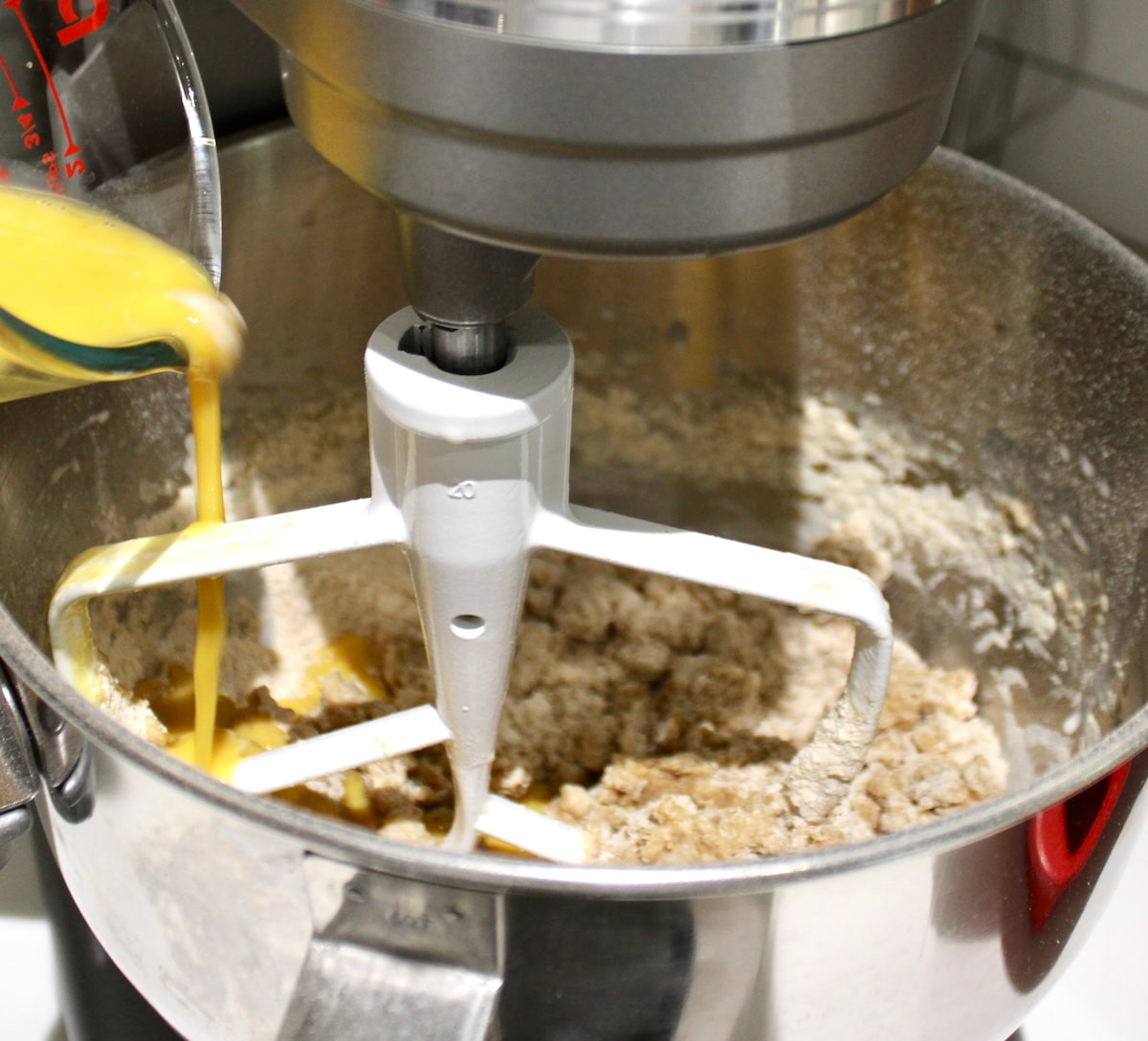beaten eggs being poured into hand mixer with dough