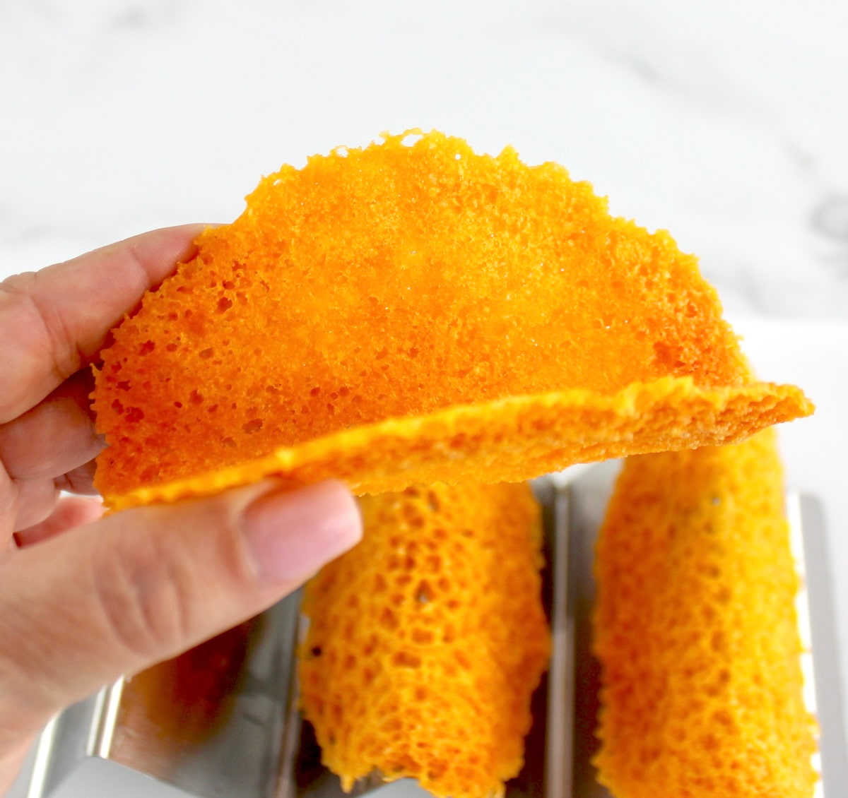 holding up Keto Cheese Taco Shell with more in background