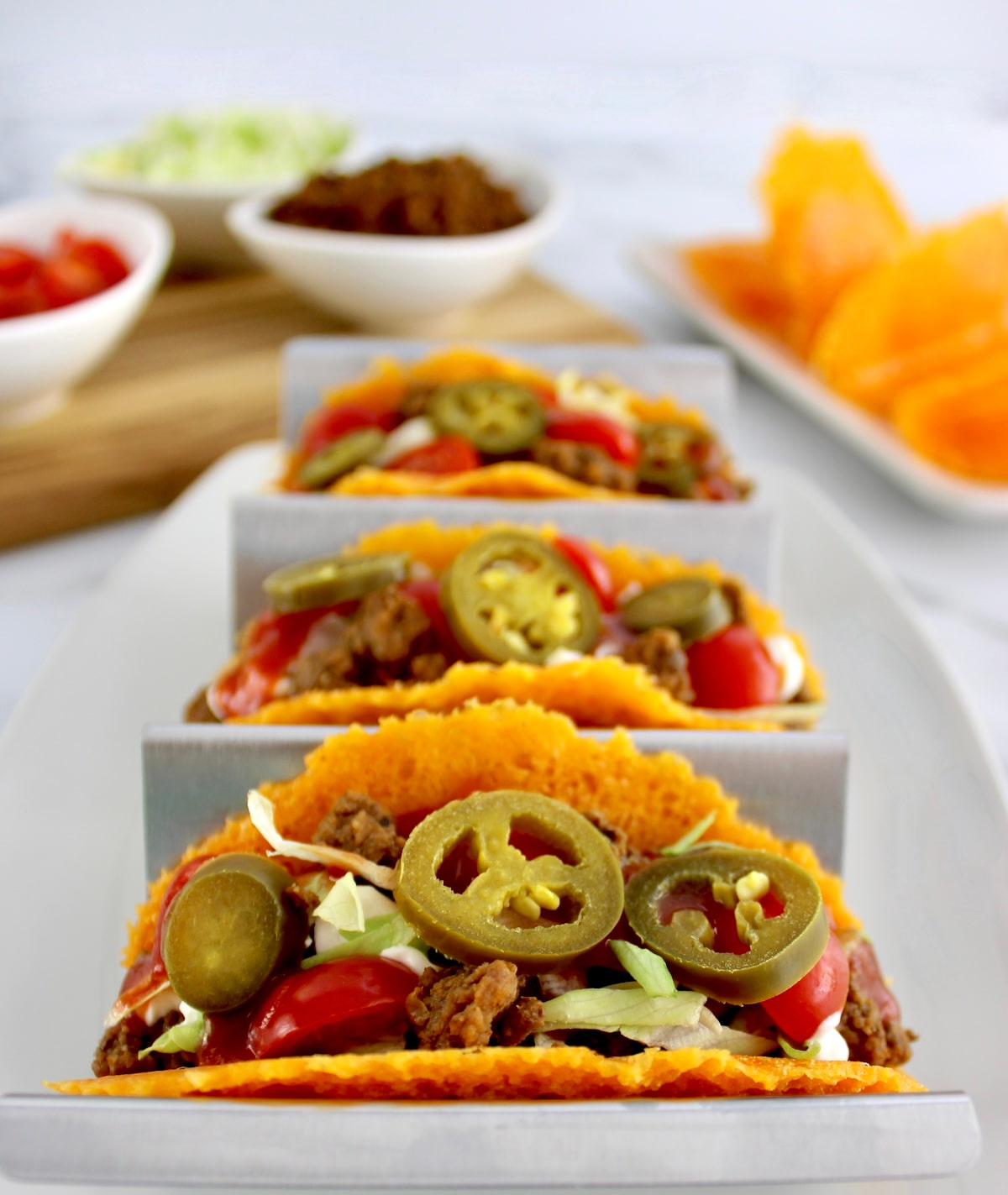 closeup of Keto Cheese Tacos in metal taco holder with toppings in back