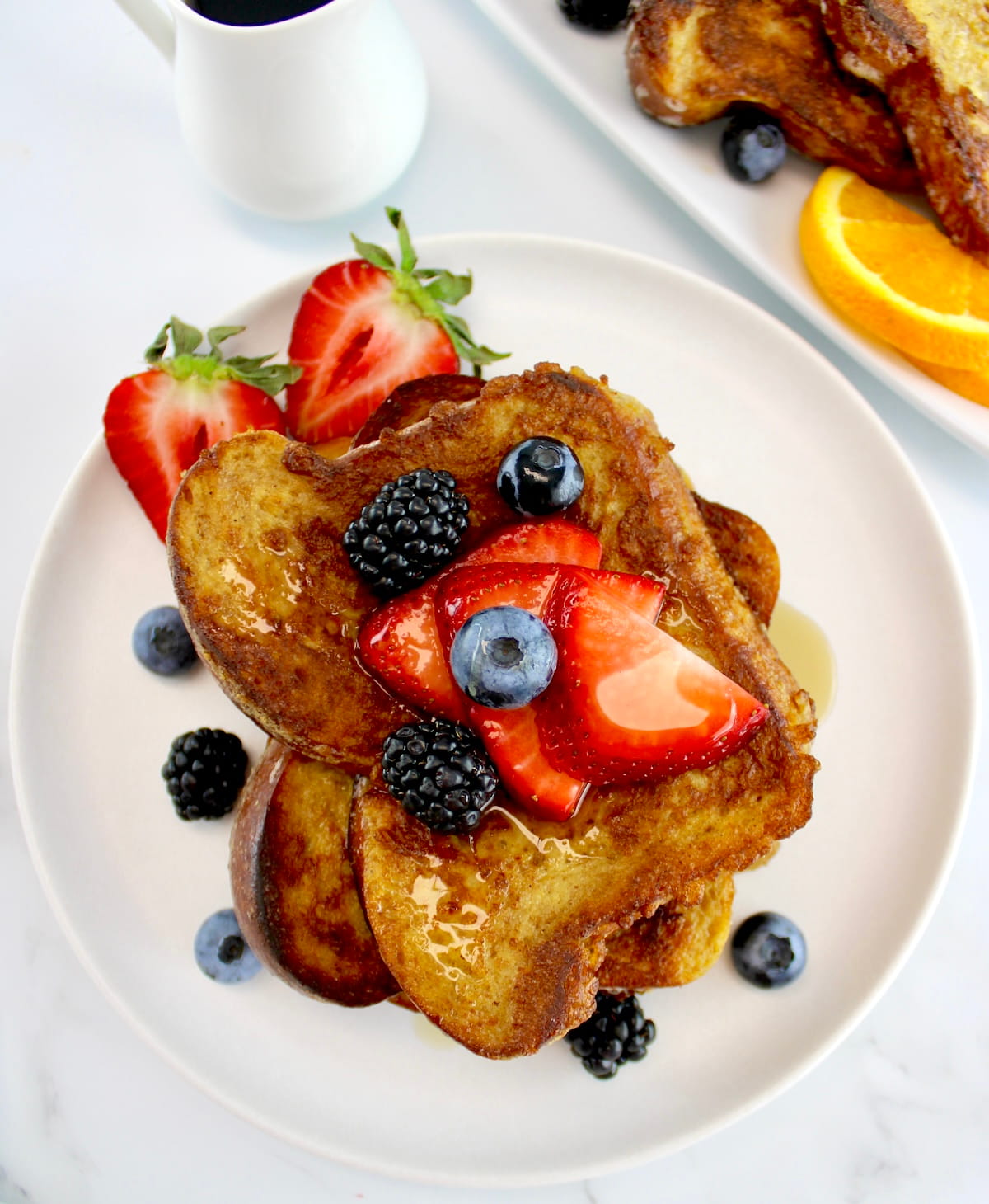 overhead closeup of Keto French Toast on white plate with fresh berries on top and around