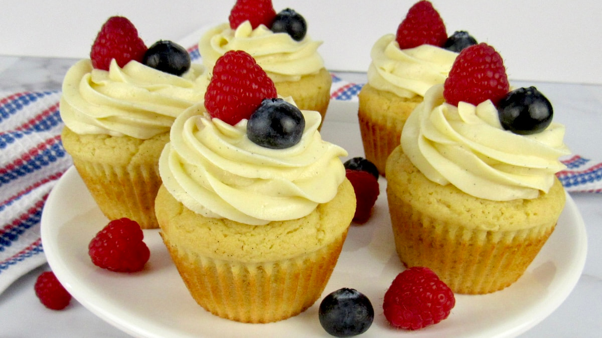 closeup of vanilla cupcake with raspberry and blueberry on top