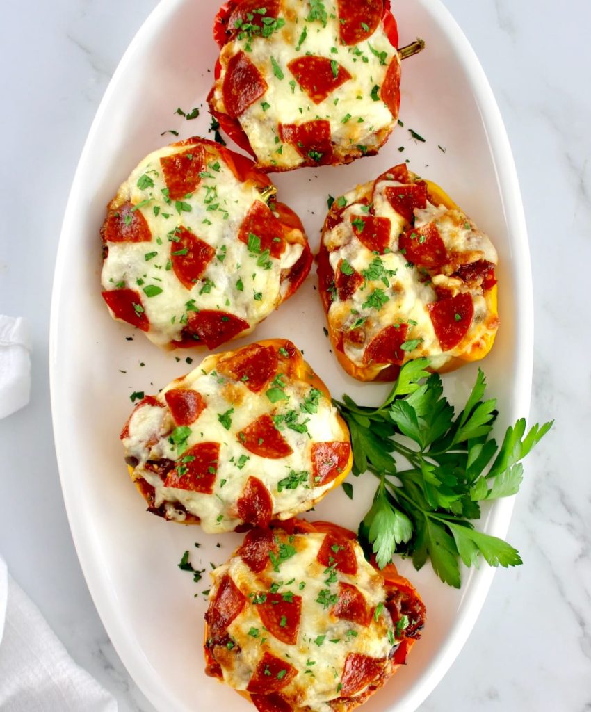 overhead view of Pizza Stuffed Peppers on white oval platter with parsley garnish