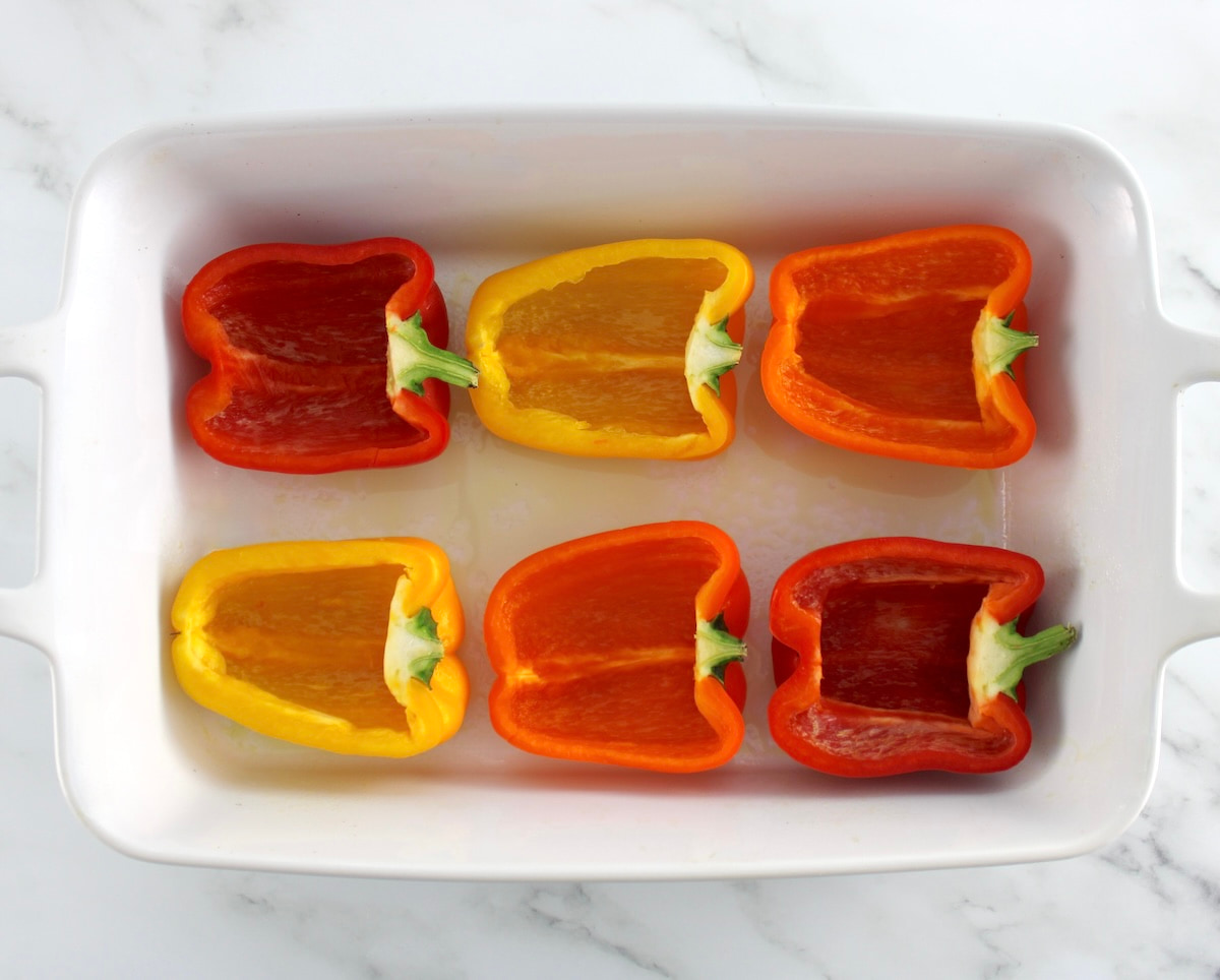 6 colored bell pepper halves in white casserole dish
