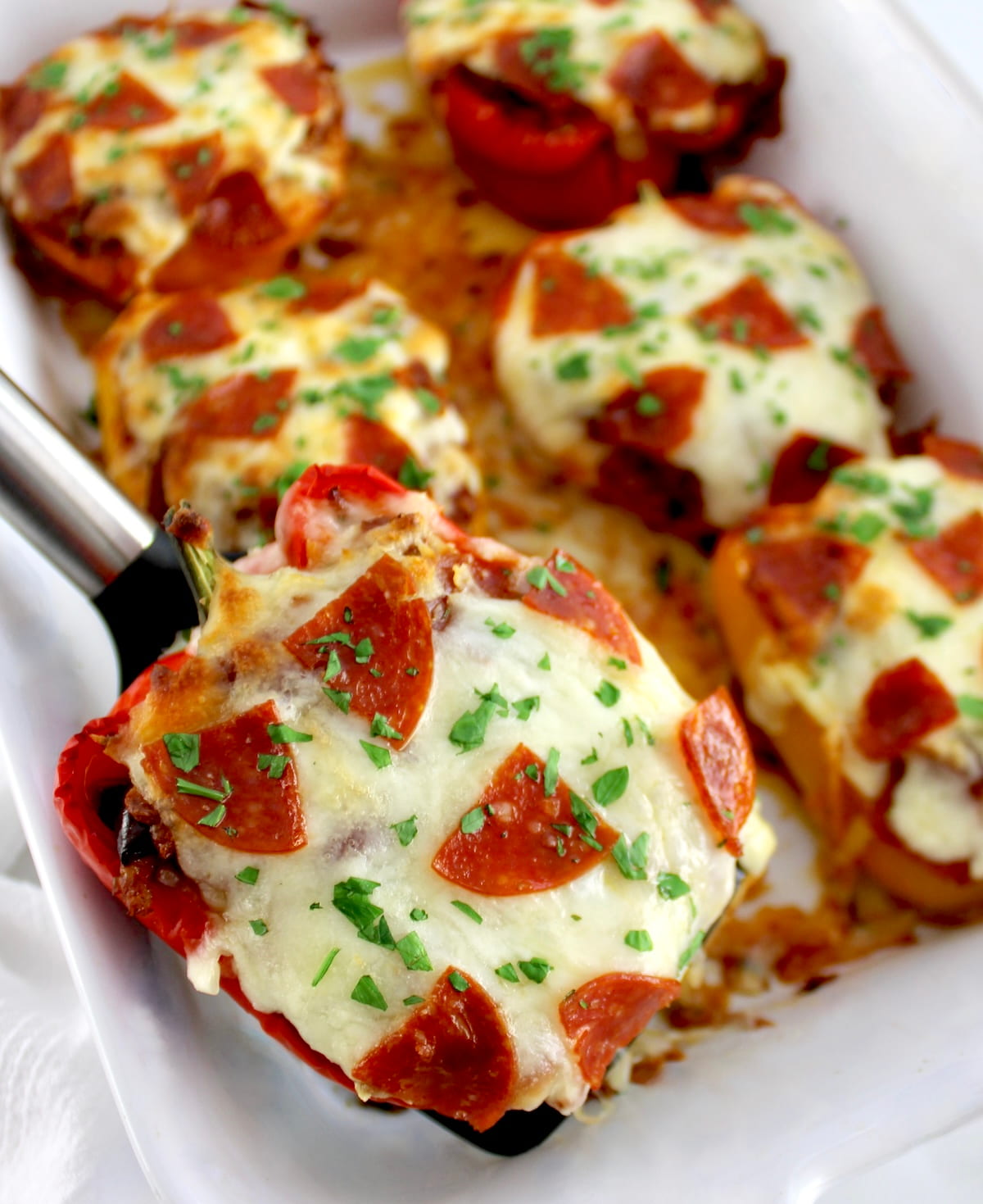 spatula lifting up Pizza Stuffed Pepper out of white casserole