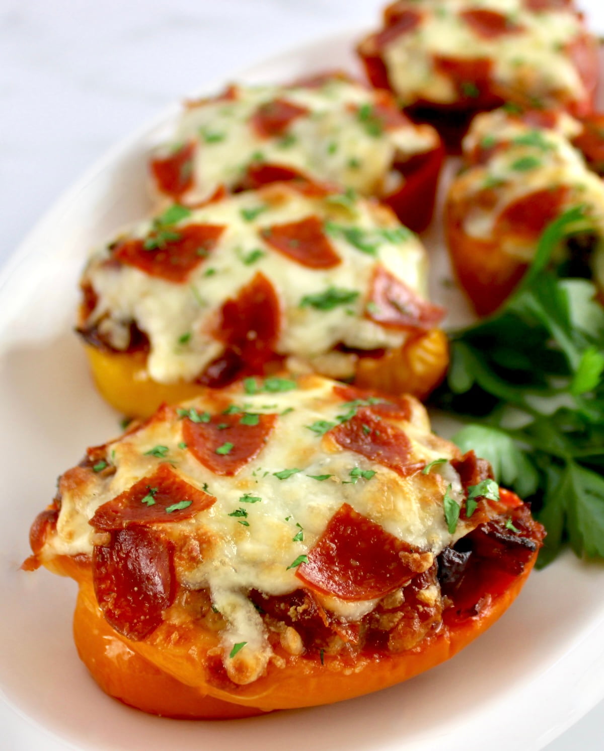 closeup of Pizza Stuffed Peppers on white plate with fresh parsley garnish