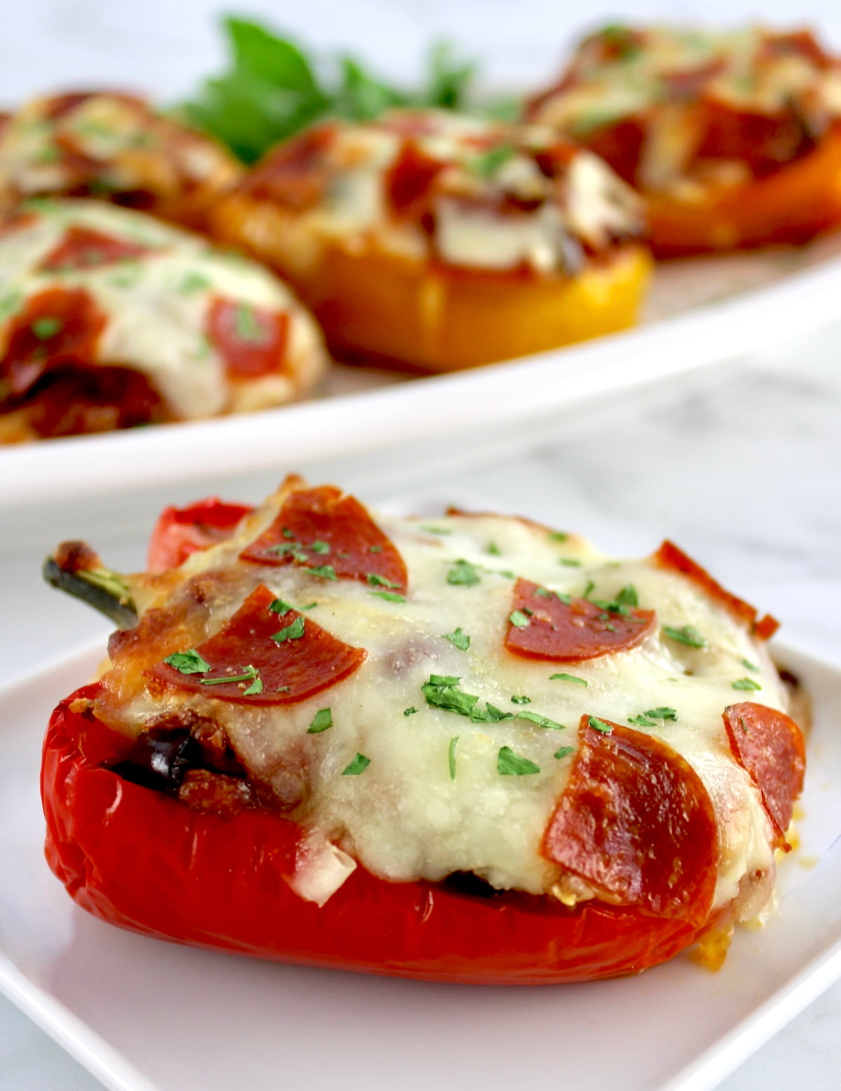 closeup of Pizza Stuffed Pepper on white plate with more in back