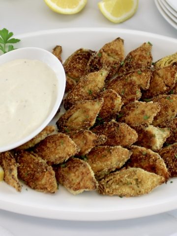 Baked Artichoke Hearts with Dipping Sauce on white oval platter with lemon slices on side