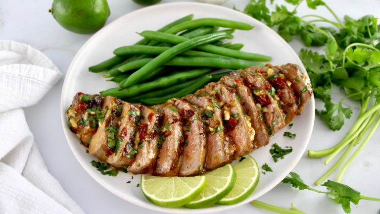 Horizontal image of grilled and sliced steak with chimichurri sauce on top