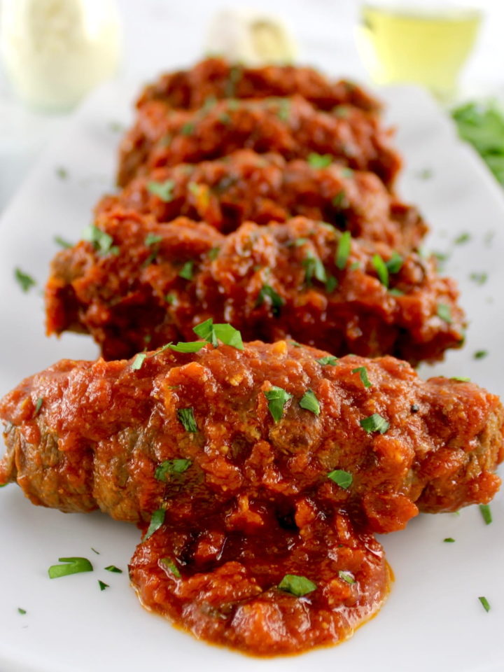 Italian Beef Braciole on long white plate with chopped parsley