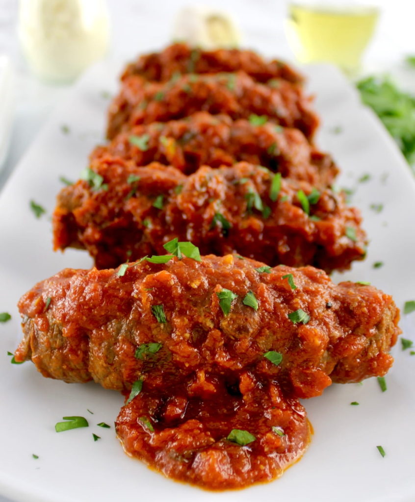 Italian Beef Braciole on long white plate with chopped parsley