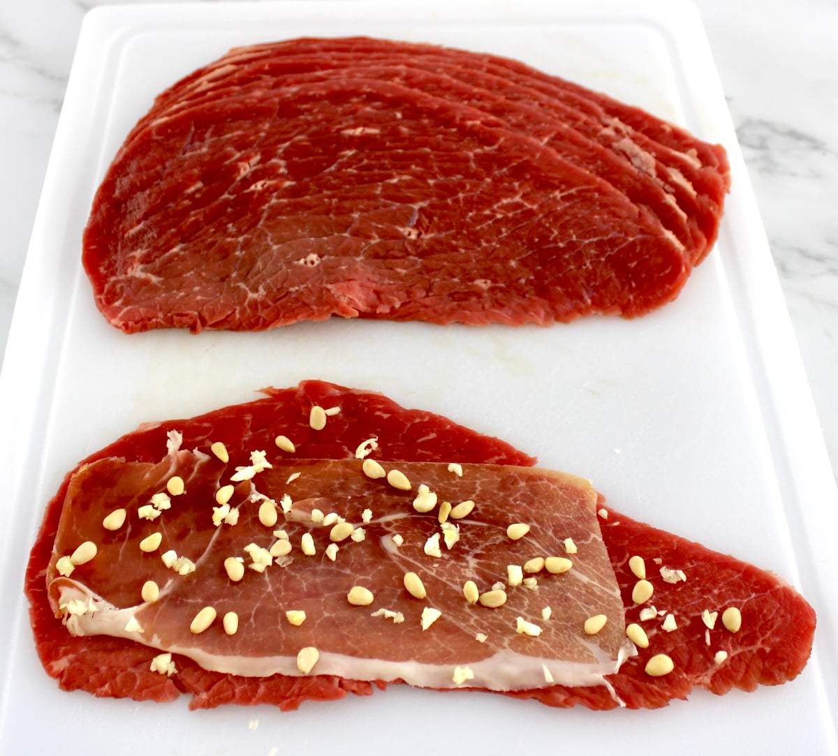 sliced beef with prosciutto, pine nuts and minced garlic on top