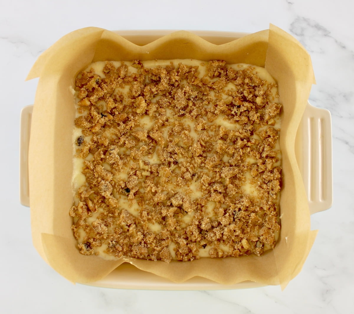 Keto Coffee Cake unbaked in baking dish lined with parchment paper