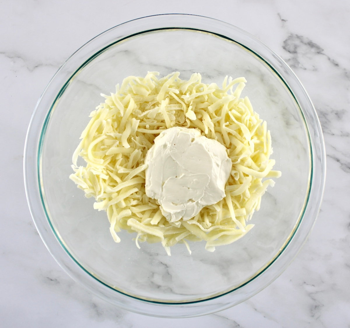 shredded mozzarella cheese and cream cheese in glass bowl