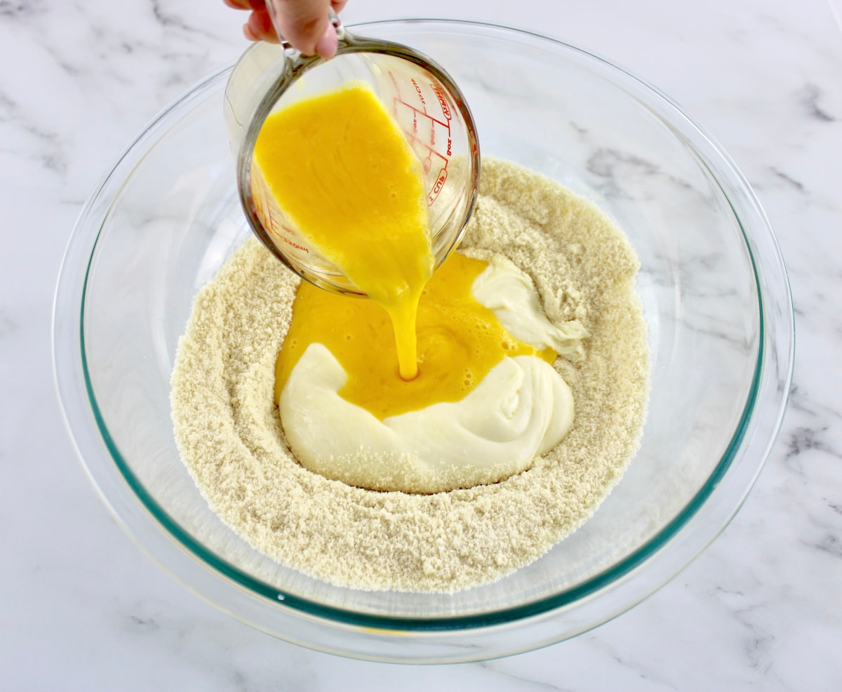 fathead dough ingredients with beaten eggs being poured into glass bowl