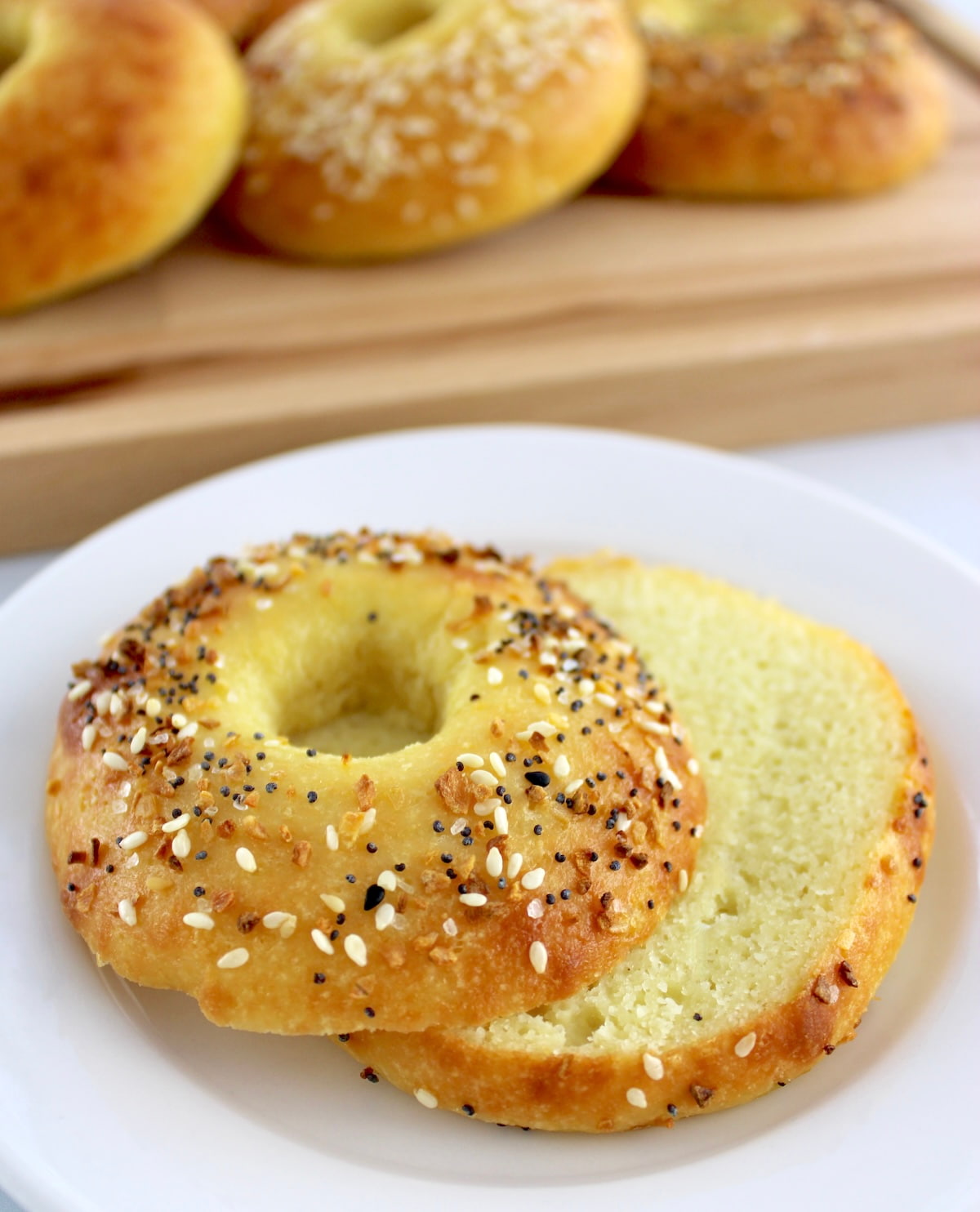 Keto Fathead Bagel cut in half on white plate with more in back