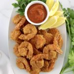 overhead view of Keto Fried Shrimp with Cocktail Sauce in white bowl with lemon wedges