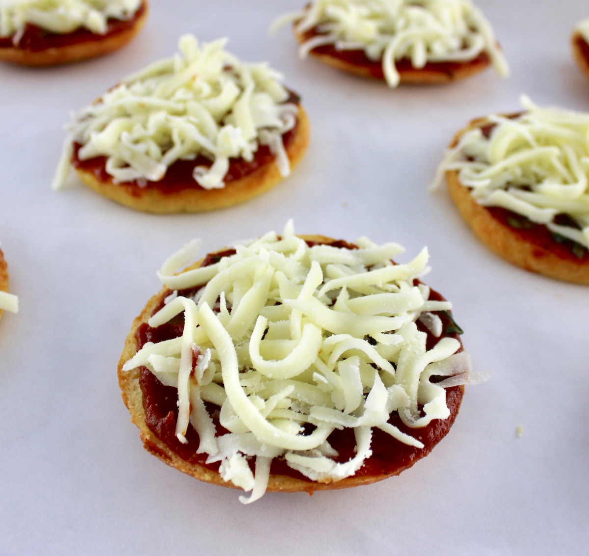 bagel halves with pizza sauce and shredded mozzarella on top